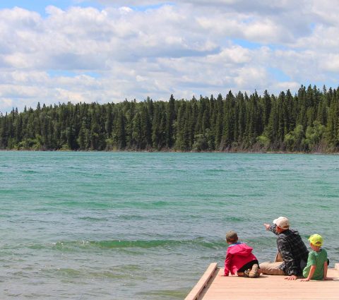 Sentado en el muelle con los niños, mirando el agua en el Parque Provincial de Duck Mountain.