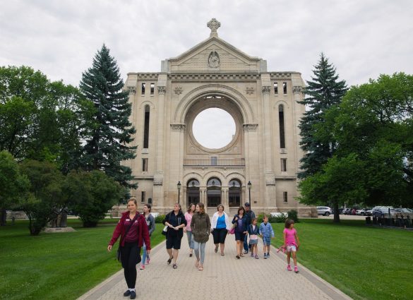 Grupo de personas disfrutando de un paseo frente a la catedral de San Bonifacio en Winnipeg.