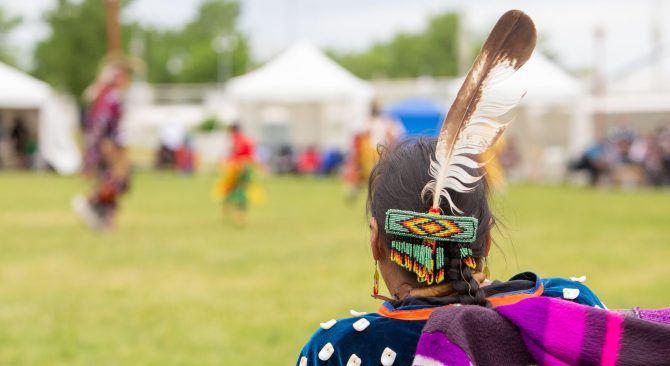 La parte posterior de una cabeza con una larga trenza y una pluma de águila; como la persona que lleva el atuendo tradicional indígena en un powwow.