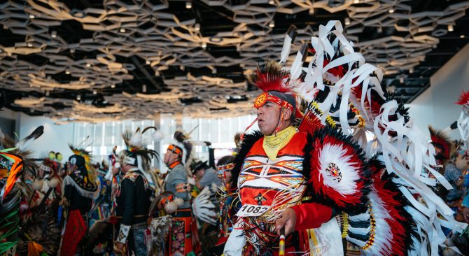 Indígena ataviado con el traje tradicional, bailando con otros en el festival pow wow de Manito Ahbee.
