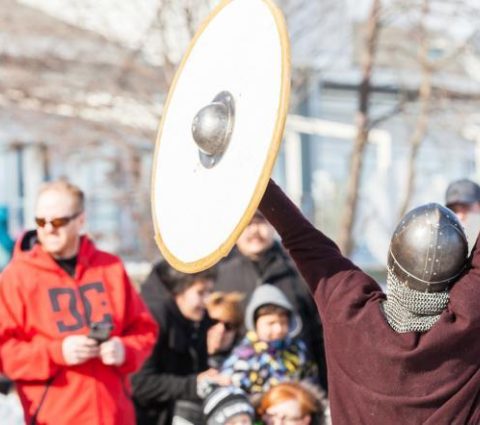 Des combats vikings palpitants se déroulent à Gimli, tandis que des piétons intrigués se rassemblent pour assister à la reconstitution historique.