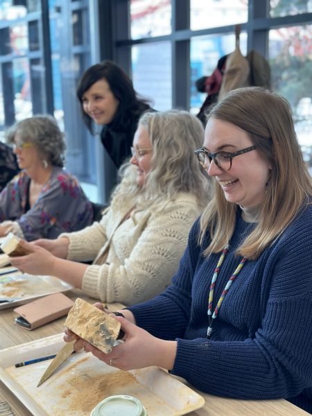 Four individuals engaged in carving wood creations at Spence's Custom Carving Workshop, showcasing their craftsmanship.