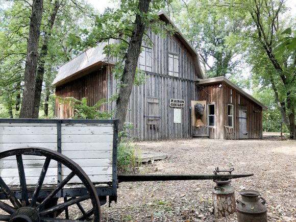 Mirando a través del patio a la Maison Goulet en forma de granero en el Museo St Pierre-Jolys.