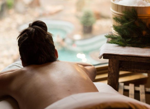 Mujer recibiendo un masaje en Thermea, con vistas a un entorno sereno.