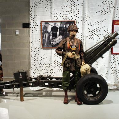 Dedicated soldier on post duty standing before an antique artillery cannon, honoring the historical legacy of the military.