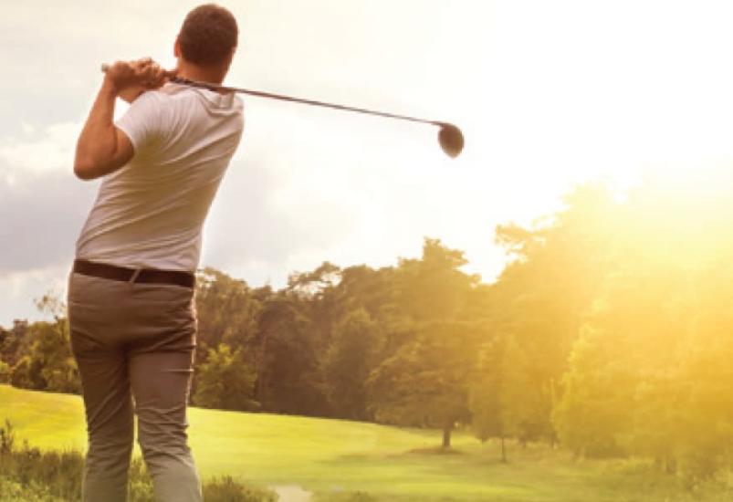 Player teeing off with perfect form on a bright day at Carberry Golf Course, showcasing skill and scenic beauty in Manitoba.