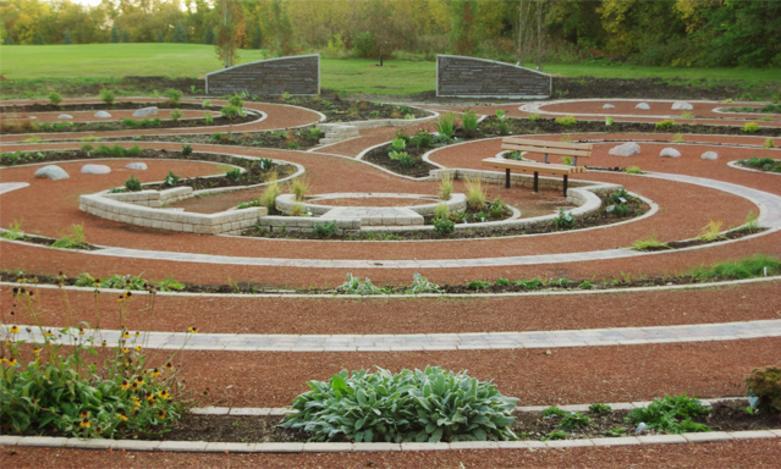 Carol Shields Memorial Labyrinth set in a tranquil landscape, featuring a winding stone path surrounded by greenery.