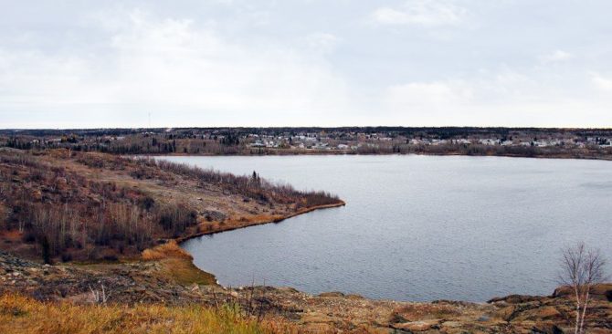 Flin Flon : Baie d'eau libre à l'automne avec une communauté urbaine en face.