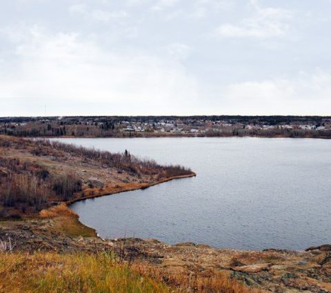 Flin Flon : Baie d'eau libre à l'automne avec une communauté urbaine en face.