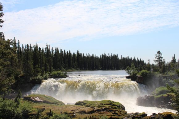 Stromschnellen eines Wasserfalls an einem klaren Tag: Die kraftvolle Schönheit der Natur stürzt inmitten einer ruhigen Umgebung in die Tiefe - ein faszinierender Anblick.
