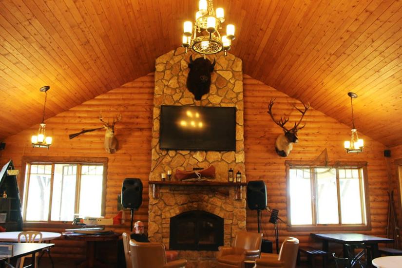Bakers Narrows Lodge innen: Rustikale Eleganz mit raumhohem Steinkamin, der gemütlichen Komfort in der Natur bietet.