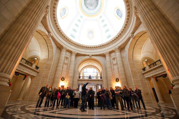 Manitoba Legislative Building interior: Crowds gather at center, symbolizing democratic engagement and civic pride.