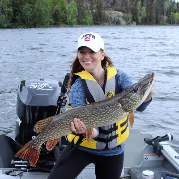 Erfolgreicher Angelausflug: Eine Person zeigt stolz einen großen Hecht, den sie in der freien Natur gefangen hat.