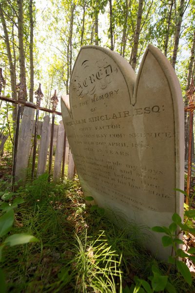 Historical gravestone in memory of William Sinclair Esq., set against a serene, natural backdrop.