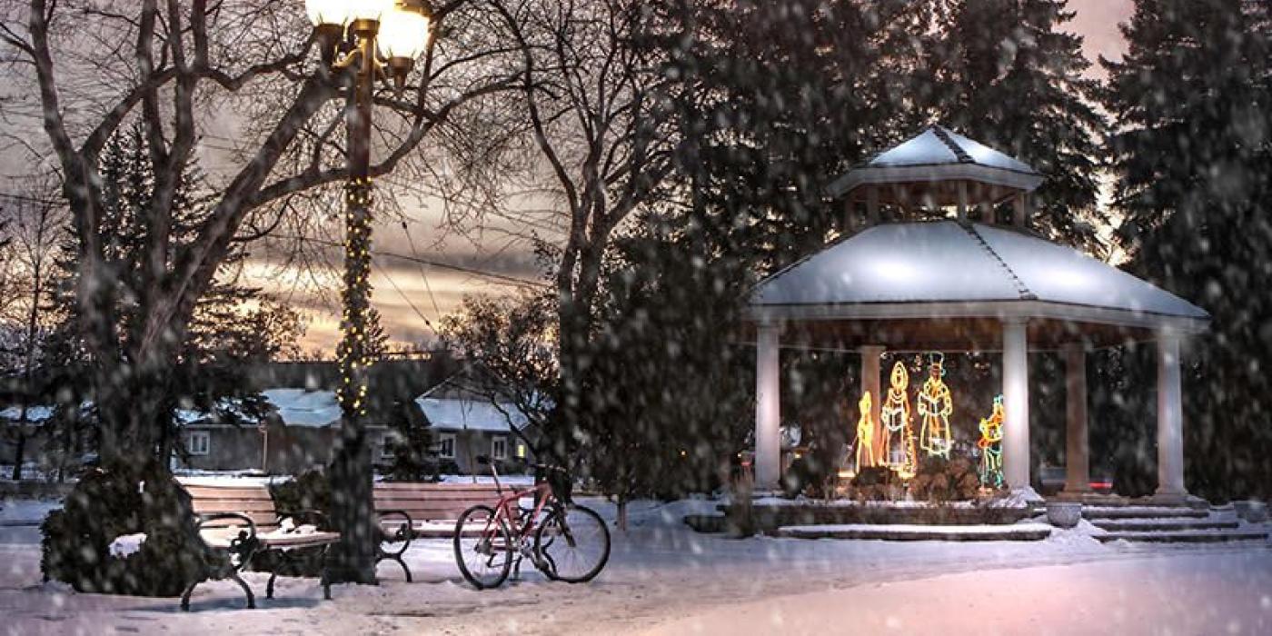 Holiday light display in a gazebo in the park while snow is falling at sunset