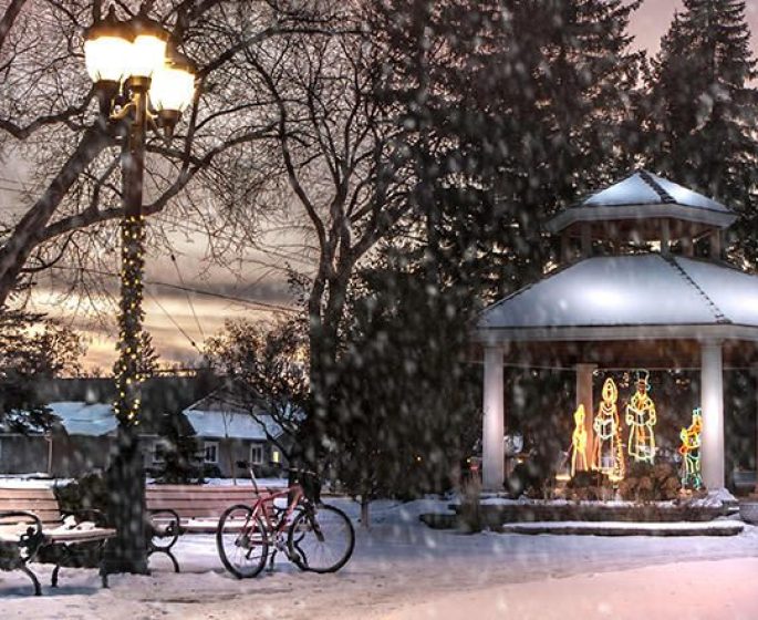 Holiday light display in a gazebo in the park while snow is falling at sunset