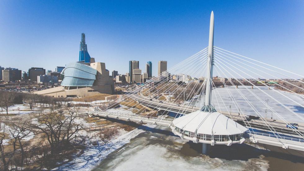 Aerial view of Esplanade Riel Footbridge, Canadian Museum for Human Rights, and downtown Winnipeg skyline amongst the melt.