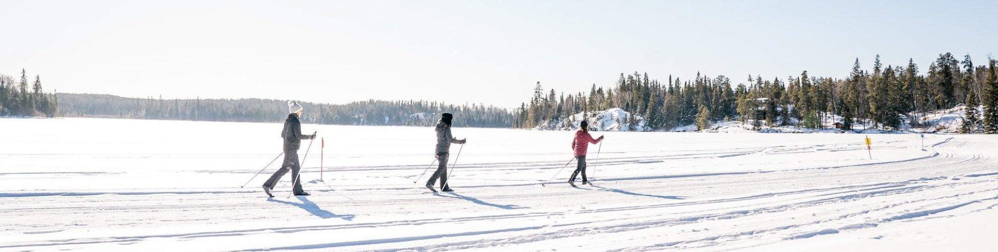 Three people cross-country skiing on a frozen lake at Falcon Trails Resort.