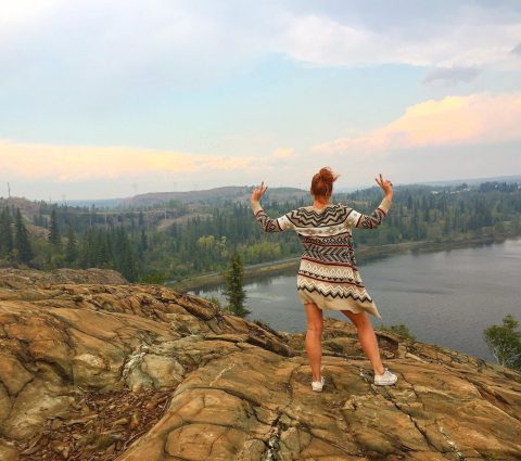 Eine Person posiert auf einer felsigen Anhöhe mit Blick auf den Fluss in der Nähe von Flin Flon.