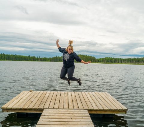 Person jumping on the end of a dock on a small lake on the Brule Trail in Riding Mountain National Park