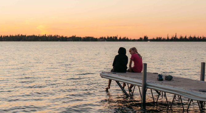 Enfants assis au bout d'un quai au coucher du soleil à The Pas, au Manitoba