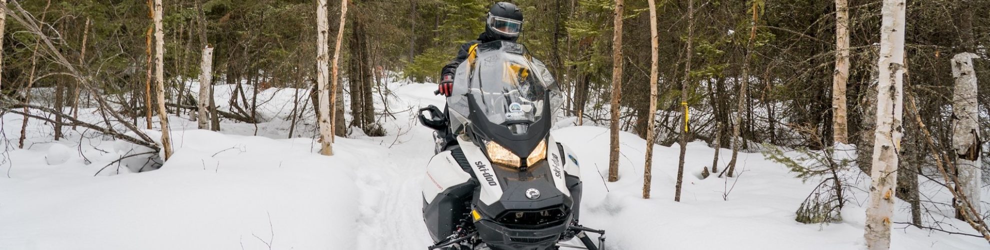 Una persona en una moto de nieve en el bosque cerca de Thompson.