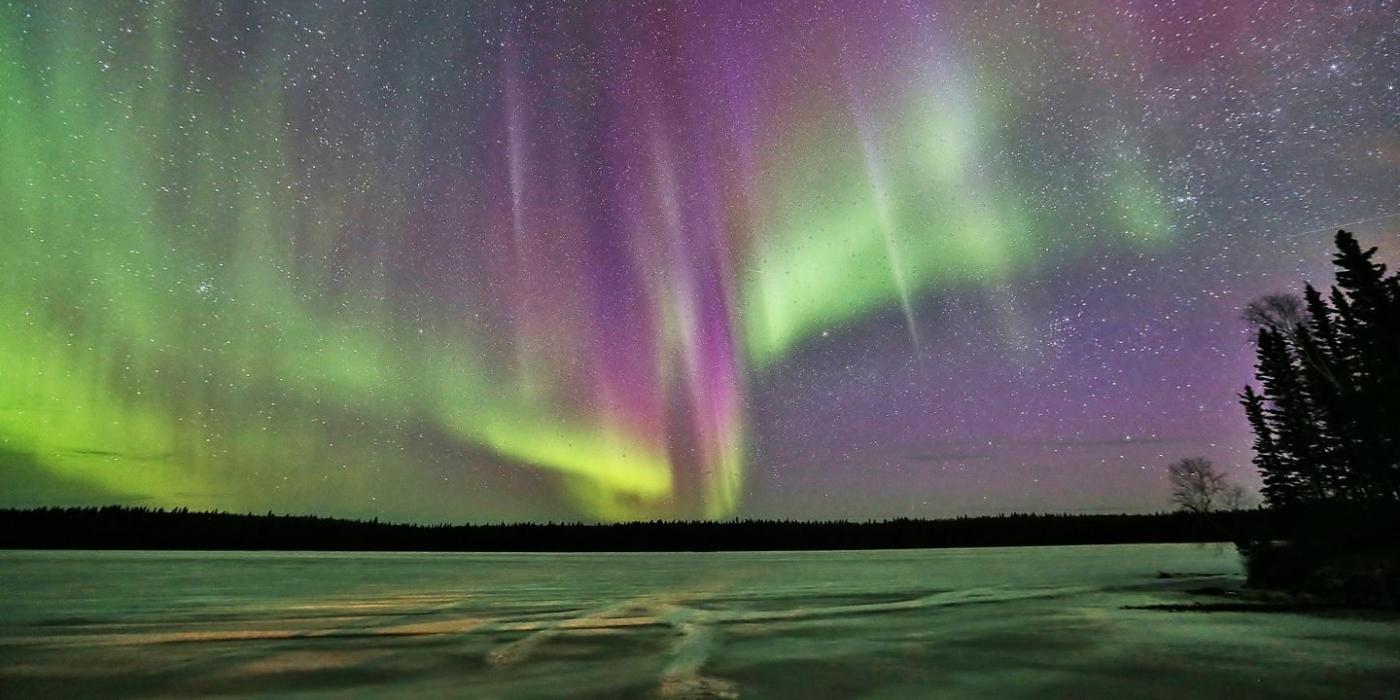 Auroras boreales en verdes y rosas sobre un lago helado.