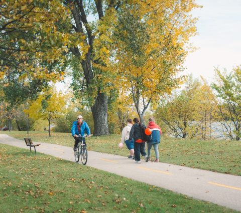 People walking and riding bikes along a path in the park, Portage la Prairie
