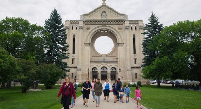 Group of people enjoying a walking tour in front of the St. Boniface Cathedral in Winnipeg