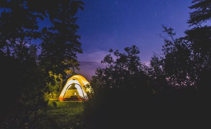 Una tienda iluminada desde dentro, resplandeciente contra un cielo oscuro.