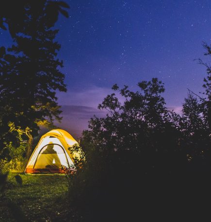 A tent lit from inside, glowing against a dark sky.