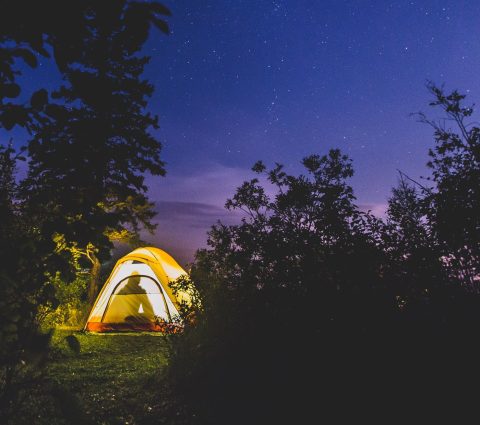 Una tienda iluminada desde dentro, resplandeciente contra un cielo oscuro.