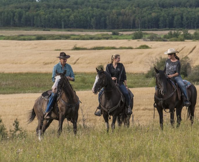 Three people on horses at 9 Finger Ranch, Manitoba