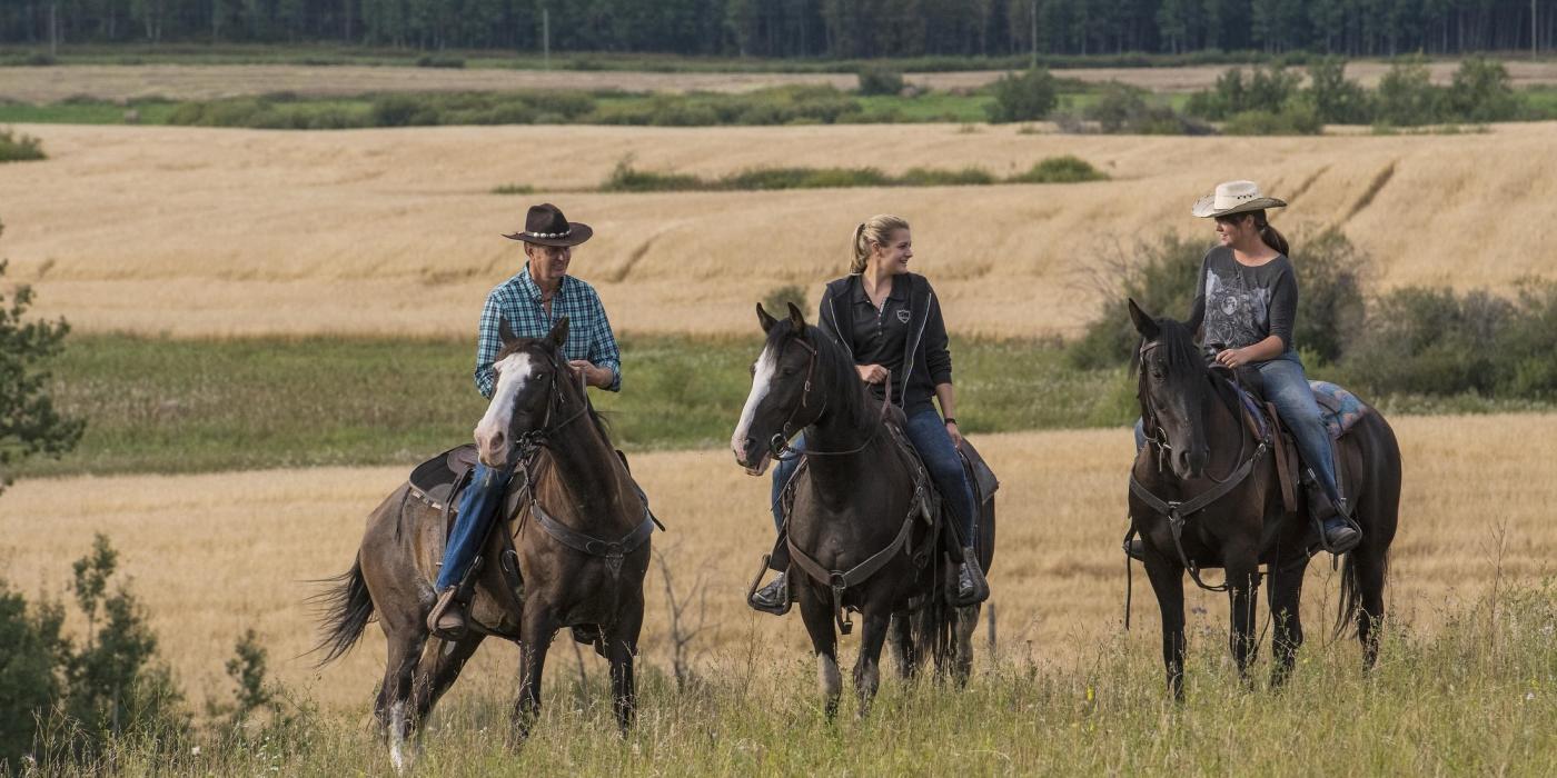 Three people on horses at 9 Finger Ranch, Manitoba