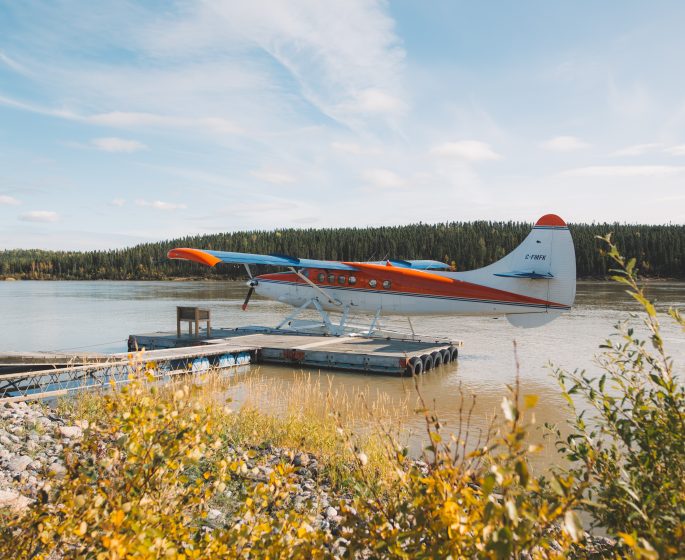 An orange and white float plane waits at the end of the dock.