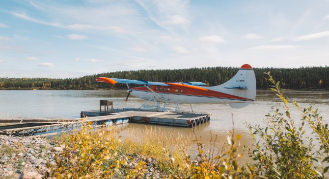 Un hidroavión naranja y blanco espera al final del muelle.