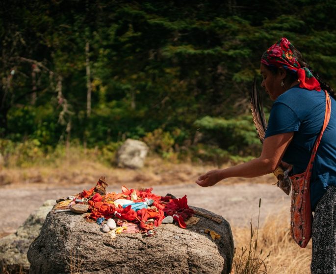A sacred offering is laid out on a rock by a person performing a blessing.
