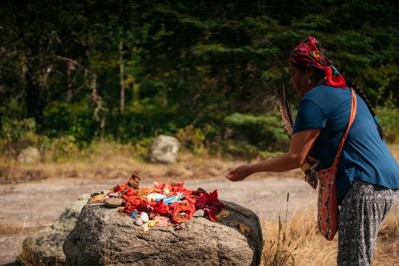 A sacred offering is laid out on a rock by a person performing a blessing.