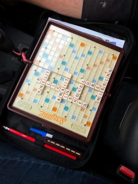 Small travel Scrabble board with eight words on it.