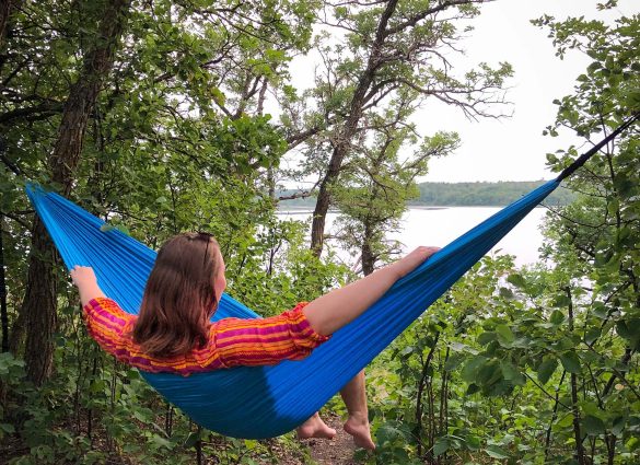 A person sitting in a hammock facing William Lake