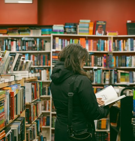 Une femme lit un livre dans l'allée de la librairie Whodunit ? à Winnipeg, Manitoba.