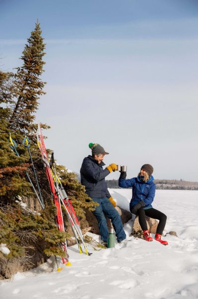 Deux personnes savourent une boisson chaude pendant une pause au cours d'une journée de ski de fond.