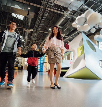 Mag-asawang naglalakad sa isang museo kasama ang kanilang anak na hawak ang kanyang kamay sa Manitoba ca