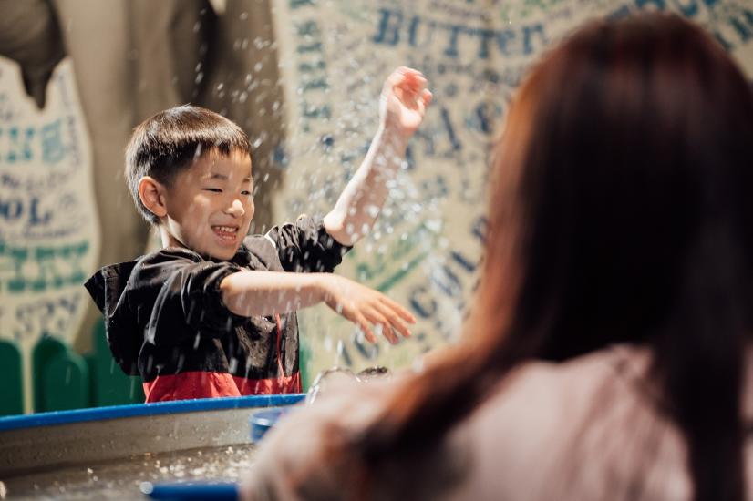 Lächelndes und planschendes Kind im Wasserbereich des Kindermuseums.