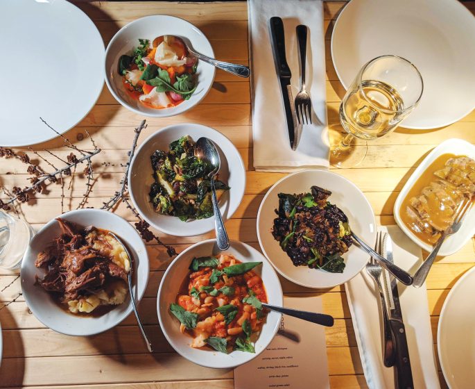 Table en bois avec quatre couverts et cinq bols remplis de nourriture.