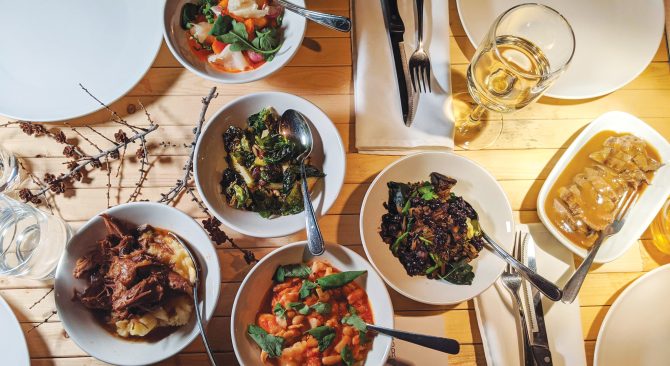 Wood table with 4 place settings and five bowls of food.