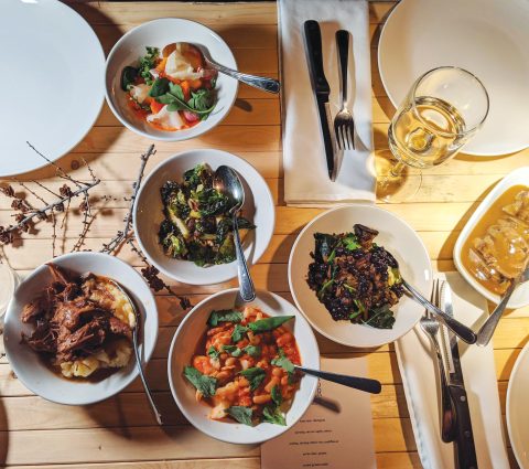 Table en bois avec quatre couverts et cinq bols remplis de nourriture.