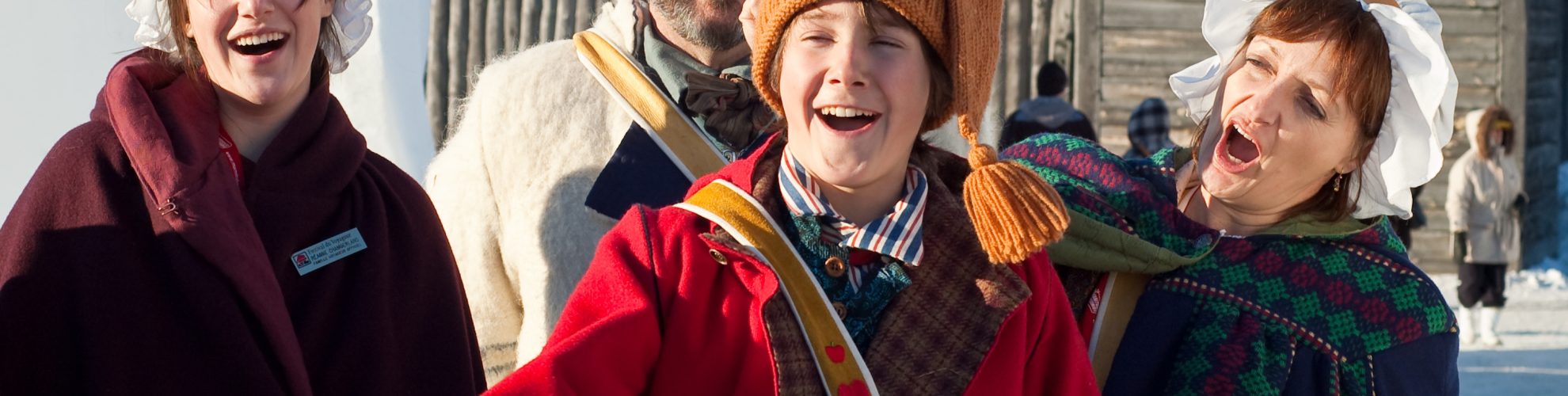 A family of four is dressed in traditional voyageur garb and 19th century fur trade winter clothing