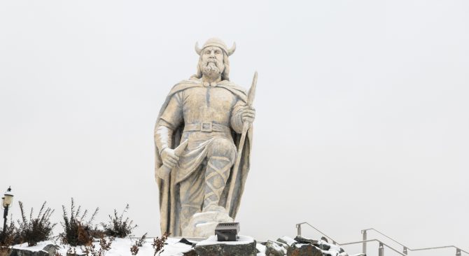 The Gimli Viking statue covered in snow, on a cloudy day.