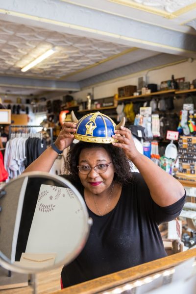 Person, die einen Wikingerhut anprobiert und in den Spiegel schaut, in Tergesens Laden in Gimli